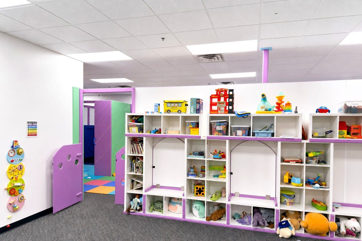 A therapy room at our Eagan clinic with low shelves of toys and a small table and chair